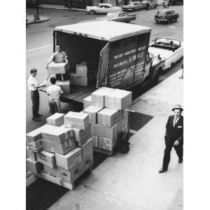  Three Men Unloading Cardboard Boxes From Back of Open 